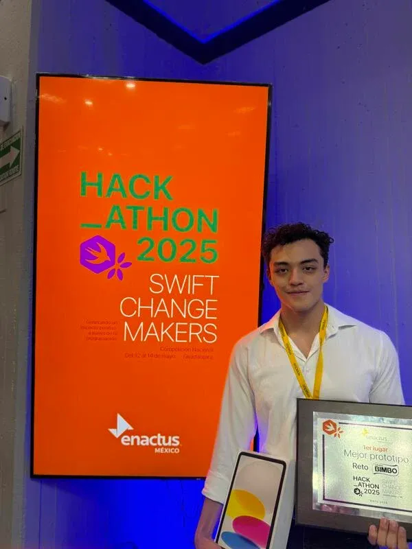 Luis con el premio de Mejor Prototipo junto al letrero de Swift Change Makers 2025